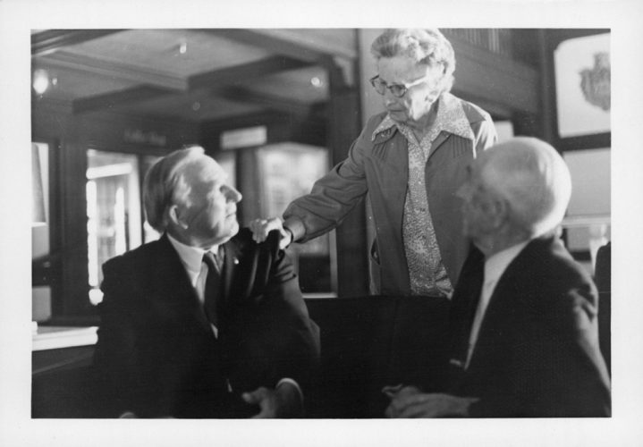 Senior woman talks with two men in suits