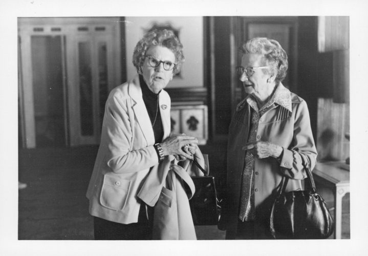 Two senior women with glasses chat