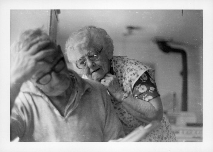 Senior woman looks over the shoulder of her husband at a paper